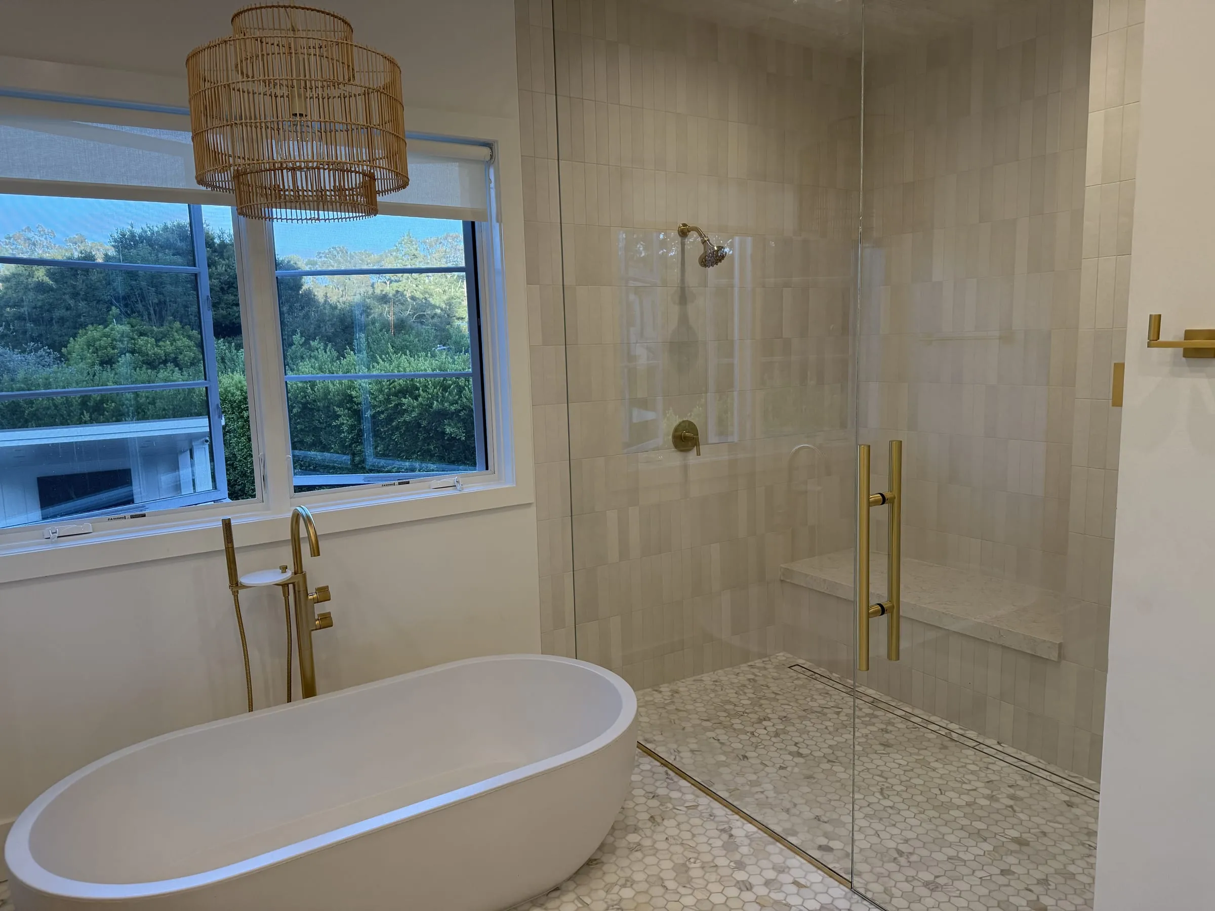 Bathroom with a freestanding tub and a frameless glass shower enclosure with brass hardware