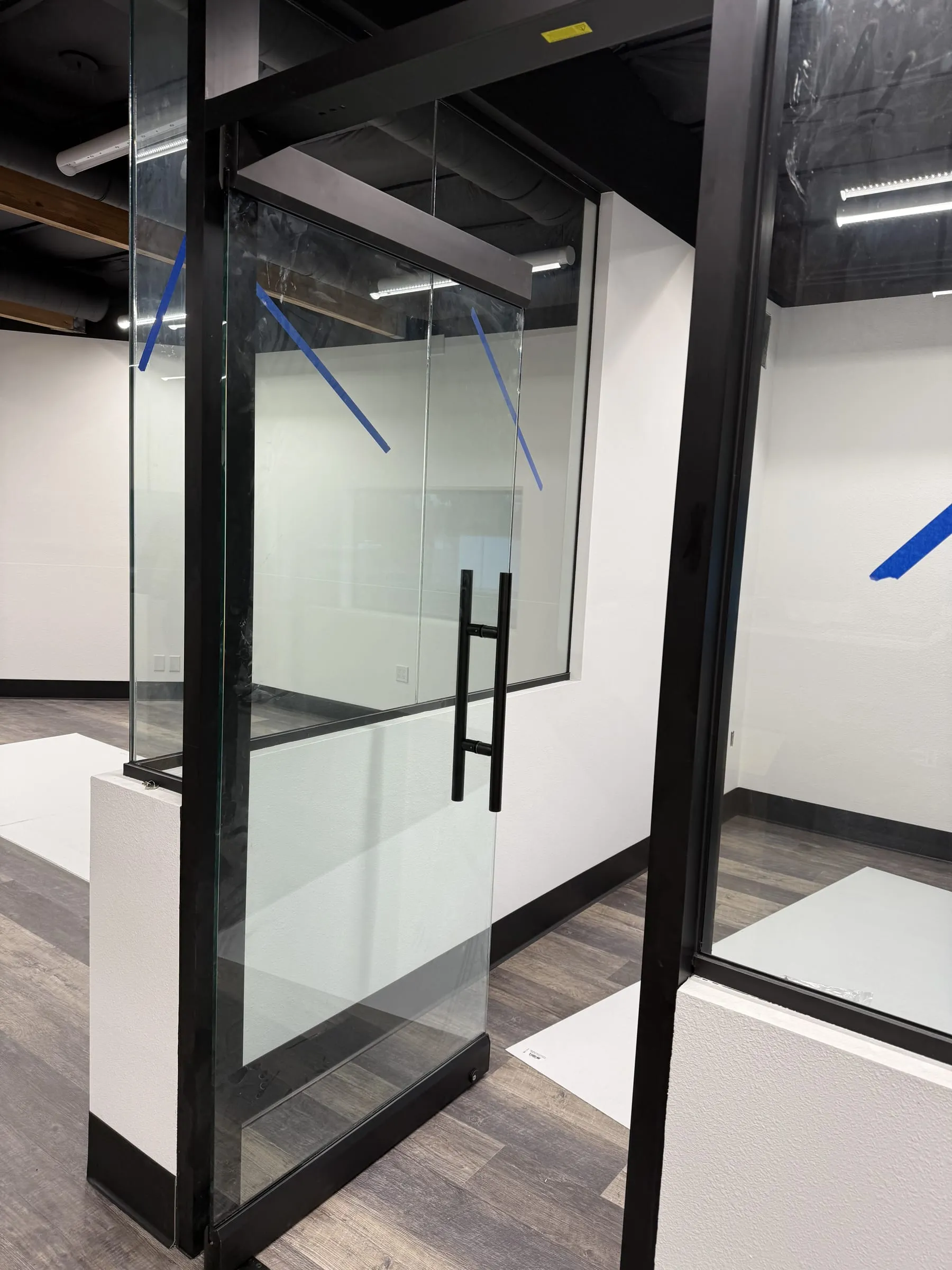 Black-framed glass door with a long pull between glass partitions
