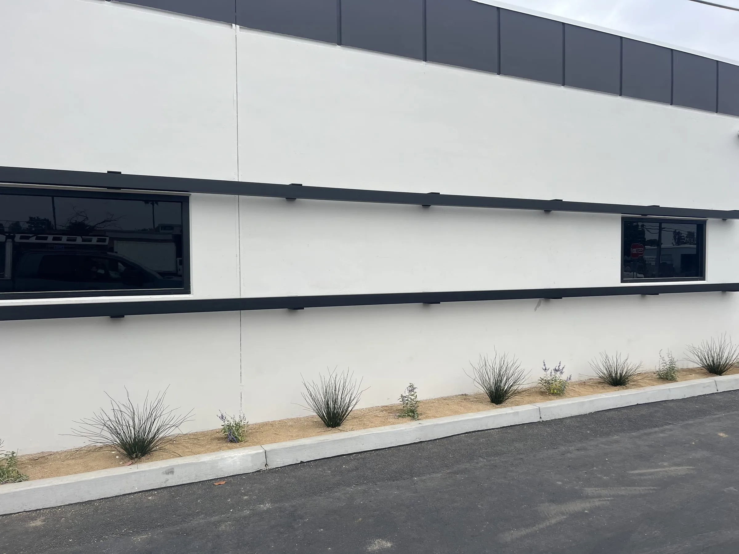 White commercial facade with black-framed windows and black trim bands