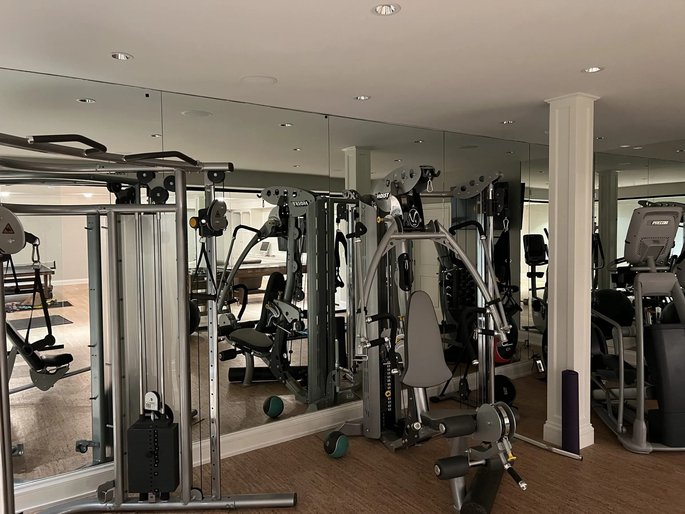 Floor-to-ceiling mirror wall behind home gym equipment