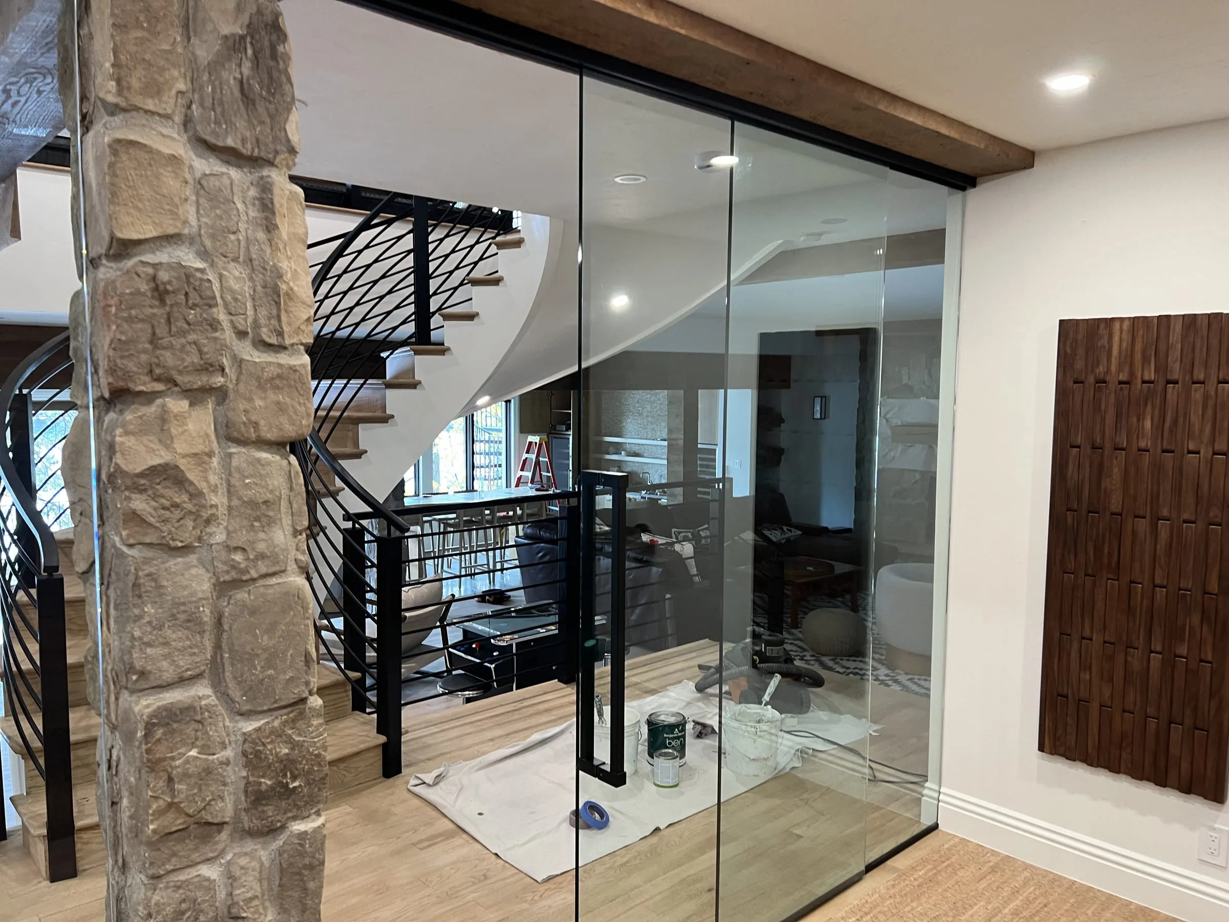 Frameless glass wall with a glass swing door beside a stone column