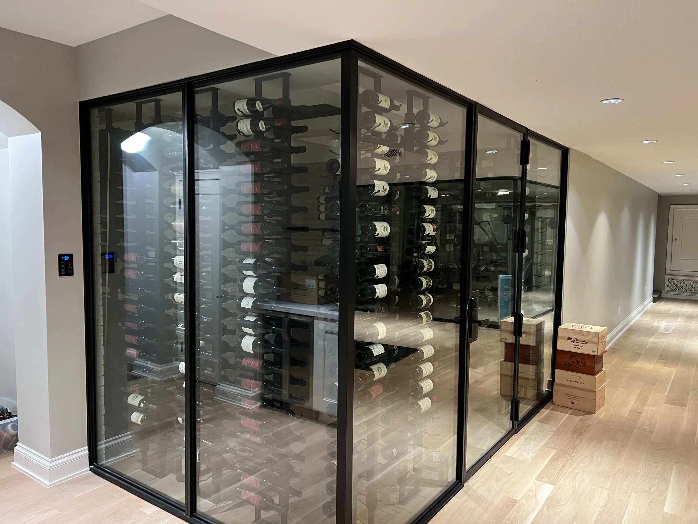 Black-framed glass wine room with a glass door and racks of wine bottles